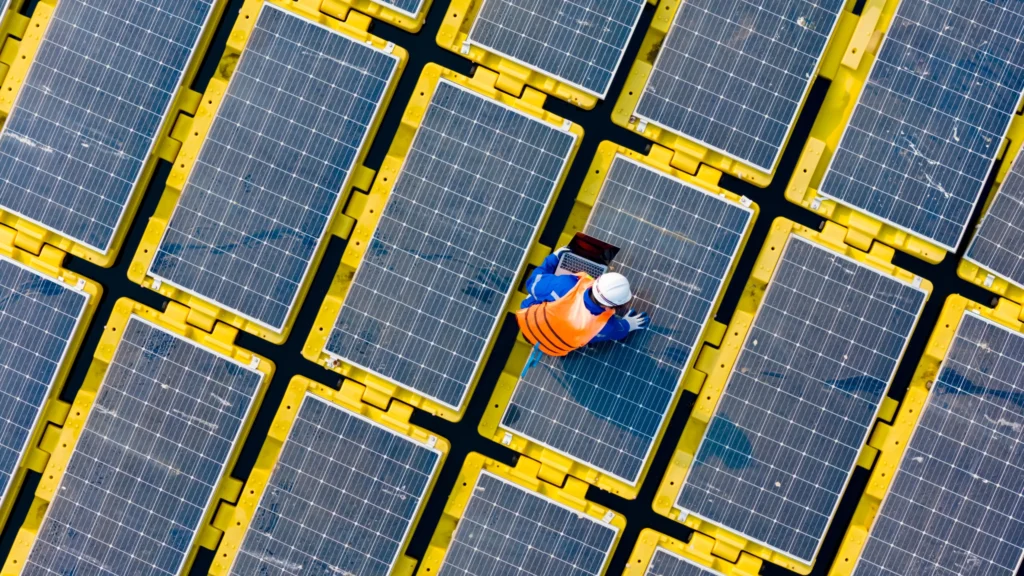 Placas solares e um engenheiro em cima delas.